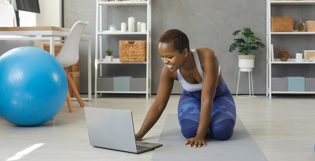 African lady with laptop doing pilates